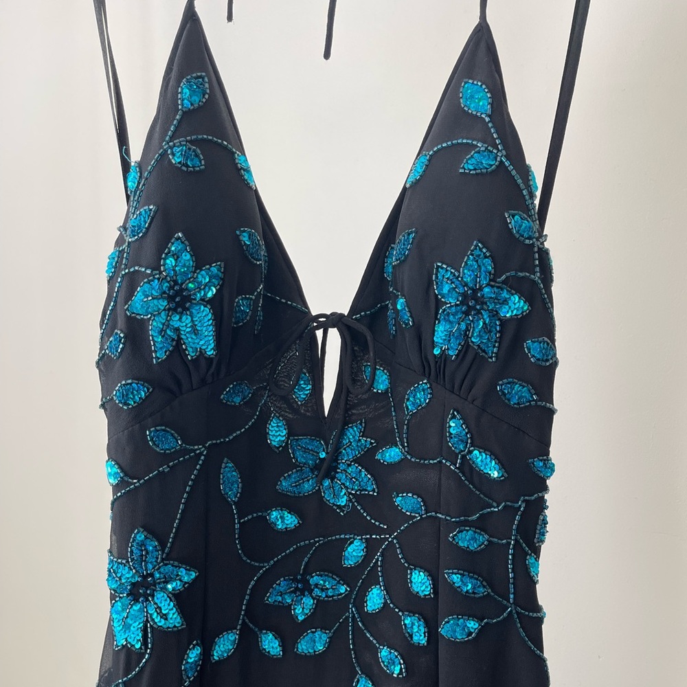 Black asymmetrical cocktail dress with blue embroidered detail.